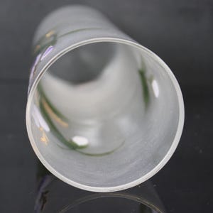 Pu&ograve; includere: Un cilindro di vetro smerigliato con accenti floreali dipinti a mano in viola, verde e giallo. La forma cilindrica &egrave; visibile da una prospettiva angolata, mostrando l'interno e la delicata opera d'arte.
