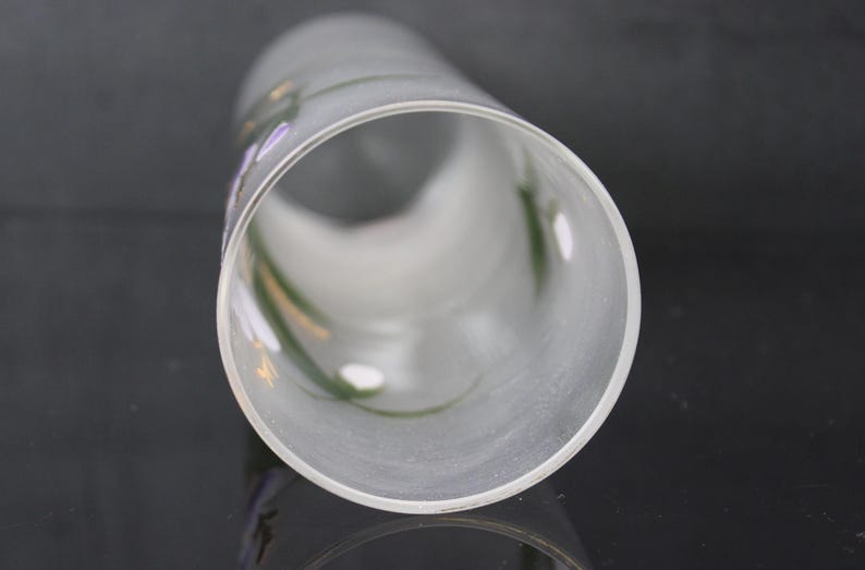 Pu&ograve; includere: Un cilindro di vetro smerigliato con accenti floreali dipinti a mano in viola, verde e giallo. La forma cilindrica &egrave; visibile da una prospettiva angolata, mostrando l'interno e la delicata opera d'arte.