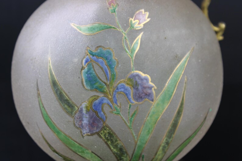 May include: A frosted glass orb with a gold-trimmed floral design. The design features blue, green, and purple irises with gold accents.