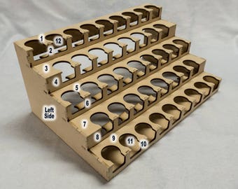 May include: A wooden paint rack with 60 individual slots for holding paint bottles. The rack is made of light brown wood and has a tiered design. The slots are numbered 1 through 12 on the left side.