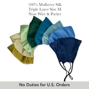 May include: A collection of eight face masks arranged in a fan shape, featuring various shades of blue, green, and gold. The text reads 100% Mulberry Silk Triple Layer Size M Nose Wire & Pocket. Each mask includes black ear loops and a nose wire.