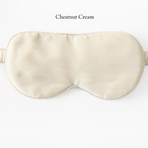 May include: A light beige silk sleep mask with an elastic strap. The mask is designed to block out light and promote sleep.