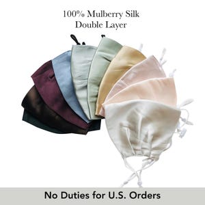 Peut inclure: Une collection de masques faciaux double épaisseur en 100% soie de mûrier, disposés en éventail. Les masques présentent une variété de couleurs dont le noir, le violet foncé, le bleu, le vert clair, le sauge, l'or, le rose et le blanc, avec des élastiques blancs réglables.