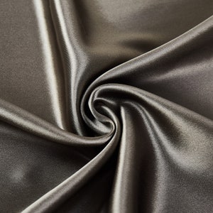 May include: Close-up of a smooth, dark gray satin fabric with soft folds and wrinkles.