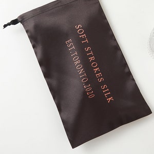May include: A black satin drawstring bag with the text "Soft Strokes Silk Est. Toronto 2020" printed in pink.