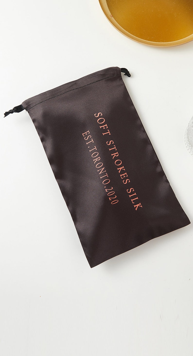 May include: A black satin drawstring bag with the text "Soft Strokes Silk Est. Toronto 2020" printed in pink.