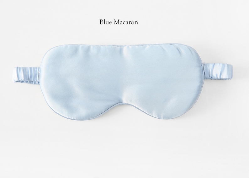 May include: A light blue sleep mask made of silk. The mask has an elastic strap.
