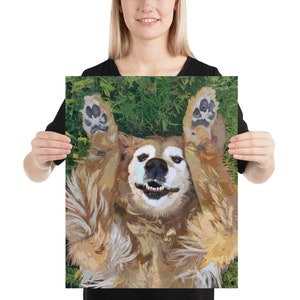 May include: A golden retriever dog lying on its back with its paws in the air, smiling with its tongue out. The dog is on a green grassy background.