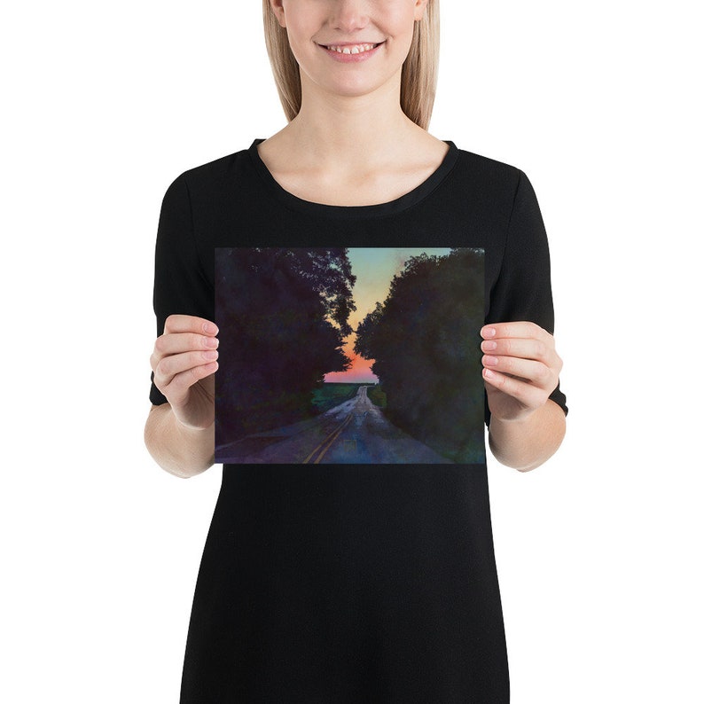 May include: A long, paved road lined with trees leads to a colorful sunset in the distance. The road is empty and the trees are dark green.