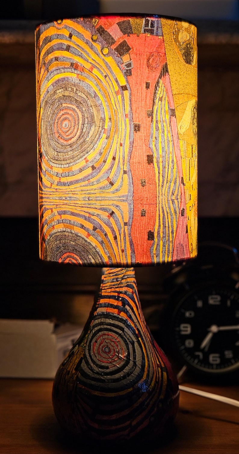 May include: A table lamp with a colorful, abstract patterned lampshade and a pear-shaped base with a similar pattern. The lamp is on a wooden surface.