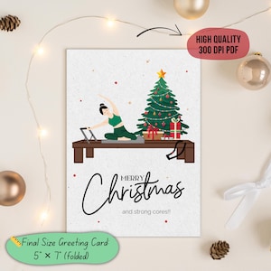 Könnte beinhalten: Weihnachtsgrußkarte mit Fitness-Thema. Die Illustration zeigt eine Person, die Pilates neben einem geschmückten Weihnachtsbaum macht. Auf der Karte steht „Fröhliche Weihnachten und starke Kerne!!“ Die endgültige Kartengröße beträgt 12,7 cm x 17,8 cm (gefaltet).