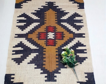 May include: A rectangular rug with a geometric pattern in shades of brown, black, and white. The rug has a fringe border.