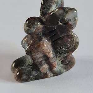 Könnte beinhalten: Eine kleine, kunstvoll geschnitzte Steinskulptur eines Schmetterlings mit braunen, weißen und grauen Markierungen.