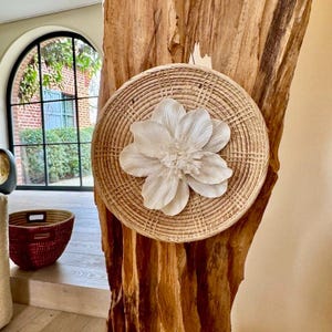 Decorazione da parete in rattan intrecciato con fiore di Sola (corteccia di legno). Diametro 31 cm. Decorazione da appendere fornita con cordino.