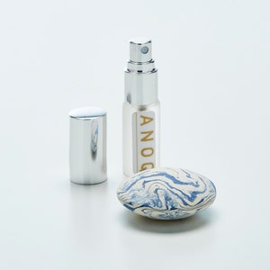 Coffret cadeau 3 pièces: un diffuseur aromatique galet, un spray de concentré de parfum 5ml, et un pochon cadeau en organza. Collection ANOQ