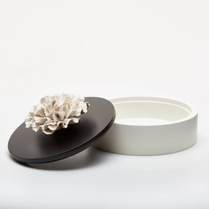 Jewel box, decorative box round shape, black and white wood with fine porcelain flower on top of the lid. BY ANOQ