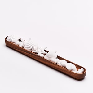 Könnte beinhalten: Ein Holztablett gefüllt mit weißen Keramikschalen und einem Seestern. Das Tablett ist braun und hat eine glatte Oberfläche.