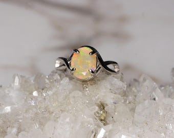 Puede incluir: Un anillo de plata con una piedra de ópalo blanco engastada en una banda retorcida.
