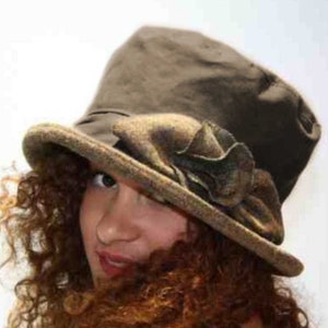 May include: A brown felt hat with a large, green and brown bow. The hat has a wide brim and a tall crown.
