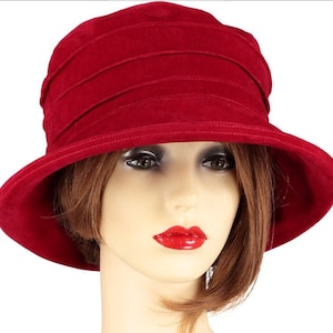 May include: A red felt cloche hat with a wide brim and a pleated crown.