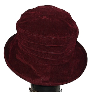 May include: A burgundy velvet hat with a wide brim and a folded crown.