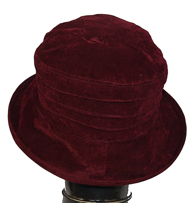 May include: A burgundy velvet hat with a wide brim and a folded crown.