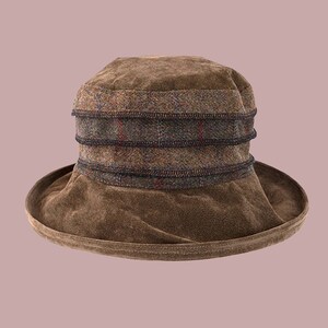 Puede incluir: Un sombrero de gamuza marr&oacute;n con una banda de tela a cuadros alrededor de la corona.