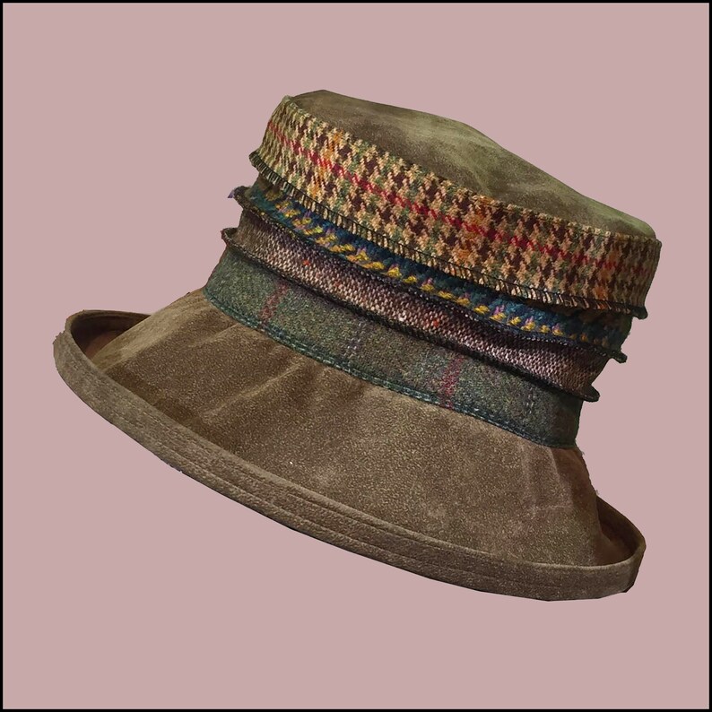 Puede incluir: Un sombrero de gamuza marr&oacute;n con un ala ancha y una banda de patr&oacute;n multicolor alrededor de la corona.