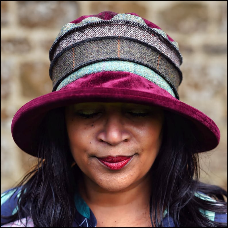 Puede incluir: Un sombrero de terciopelo burdeos con ala ancha y una banda con estampado multicolor. El sombrero est&aacute; hecho de una tela suave y lujosa y tiene un dise&ntilde;o cl&aacute;sico y elegante.