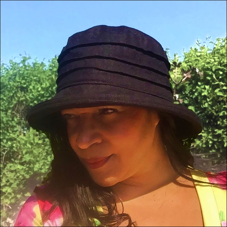 Puede incluir: Un sombrero de sol negro de ala ancha con una corona plisada. El sombrero est&aacute; hecho de una tela suave y ligera y tiene un ala ancha que proporciona una amplia sombra del sol.