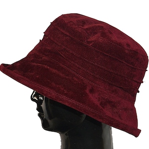 May include: A burgundy velvet sun hat with a wide brim and a pleated crown.