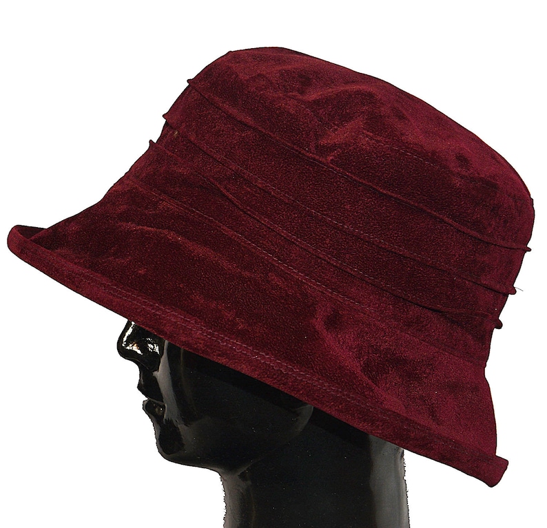 May include: A burgundy velvet sun hat with a wide brim and a pleated crown.