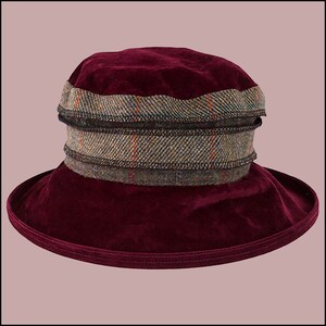 Puede incluir: Un sombrero de terciopelo burdeos con un ribete de cuadros marrones y verdes.
