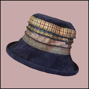 May include: A navy blue velvet hat with a wide brim and a multi-colored patterned trim. The trim is made of different fabrics, including tweed and houndstooth.