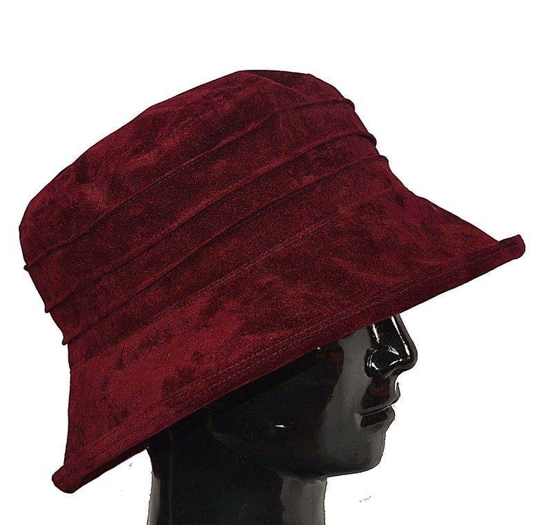 May include: A burgundy velvet bucket hat with a wide brim. The hat is made of soft, plush fabric and has a classic, timeless design.