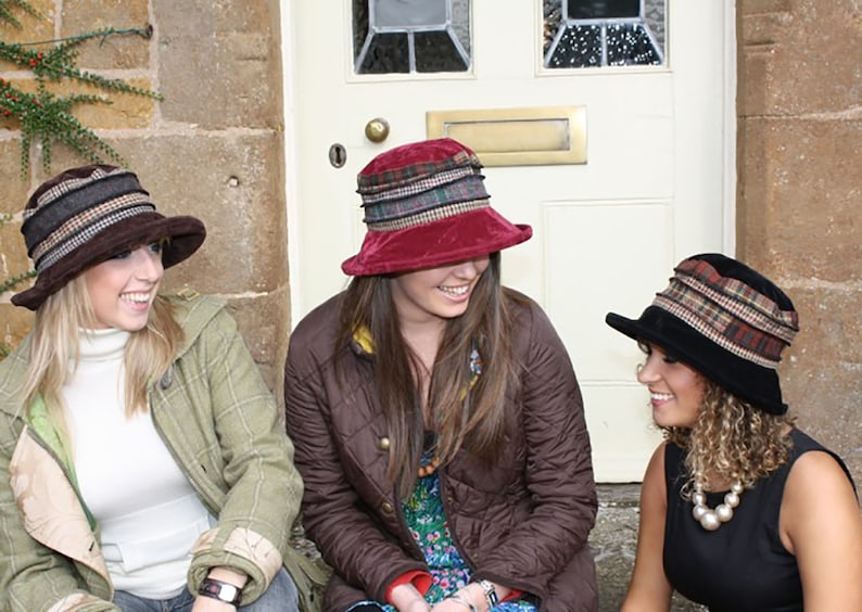 Puede incluir: Tres mujeres con sombreros de diferentes patrones. Los sombreros son todos de tela y tienen un ala ancha. Las mujeres sonr&iacute;en y miran a la c&aacute;mara.