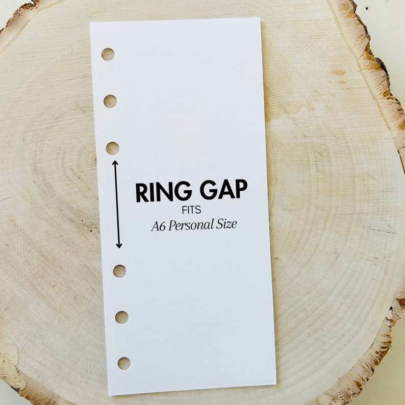 May include: White card with black text that reads "RING GAP FITS A6 Personal Size". The card has six holes along the left edge and a vertical line with arrows pointing up and down.