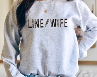 May include: A gray sweatshirt with the text "LINE WIFE" printed in black letters with a leopard print pattern. The letters are outlined in black.