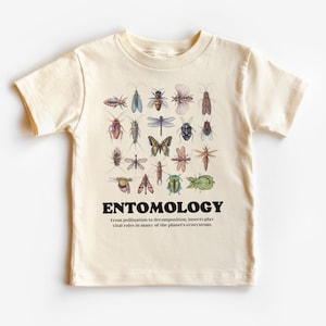 May include: A cream-coloured t-shirt featuring a graphic of various insects and the text "ENTOMOLOGY" in black. The text below the graphic reads "From pollination to decomposition, insects play vital roles in many of the planet's ecosystems."