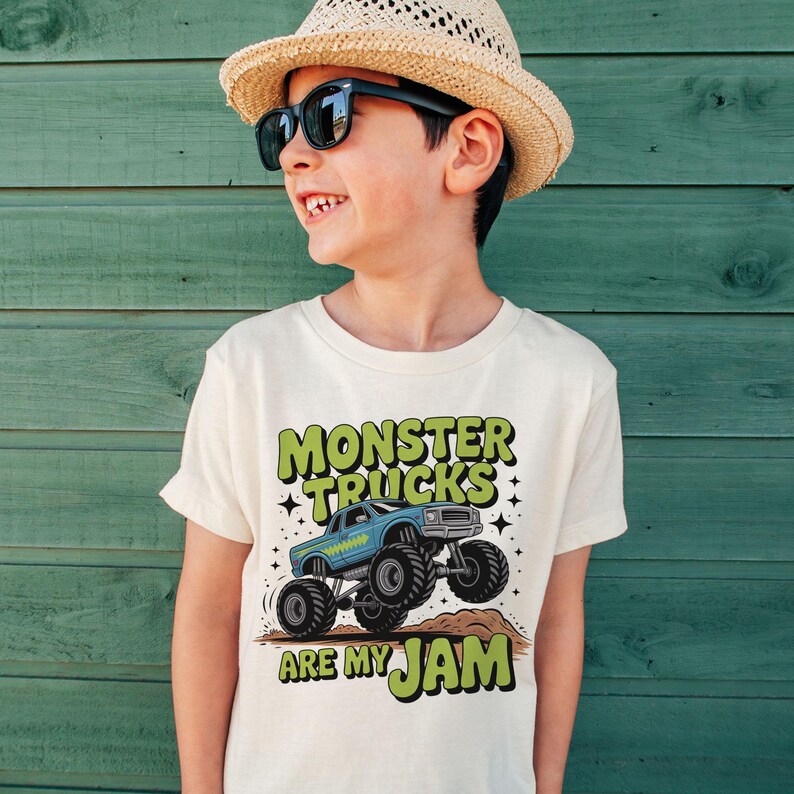 Puede incluir: Camiseta de color crema con un dise&ntilde;o de cami&oacute;n monstruo azul y el texto "MONSTER TRUCKS ARE MY JAM" en verde. La camiseta est&aacute; hecha de un material suave y es adecuada para ni&ntilde;os.