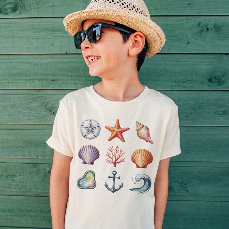 May include: A cream-colored t-shirt featuring various sea-themed illustrations. The design includes a starfish, seashells, coral, an anchor, and a wave. The shirt is worn by a person wearing sunglasses and a straw hat.