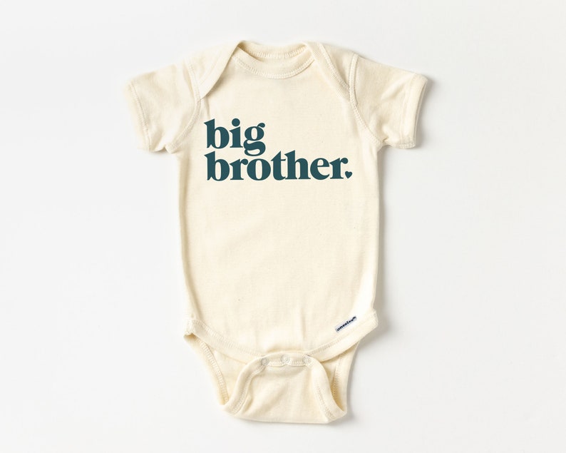 May include: A cream-colored baby onesie with short sleeves and the text "big brother" printed in dark teal.