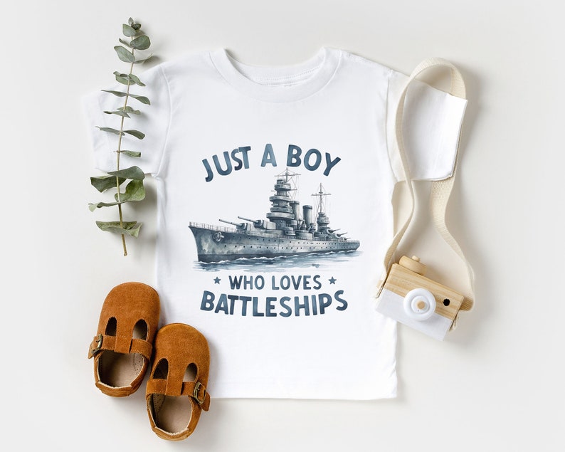 May include: White t-shirt with a blue and grey illustration of a battleship and the text "Just a boy who loves battleships".