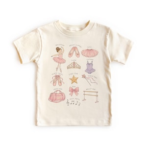 Pode incluir: Uma t-shirt de manga curta cor de creme com uma grelha de ilustrações com tema de ballet, incluindo uma bailarina, sapatilhas, tutu, tiara, collant, sapatilhas de ponta, estrela, varinha, saco de dança, laço e notas musicais com legendas.