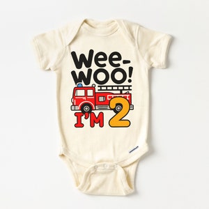 May include: A cream-colored baby onesie with a red fire truck and the text "Wee-Woo! I'm 2" in black and yellow.