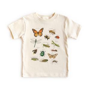 Puede incluir: Una camiseta de manga corta color crema con un estampado gráfico detallado de varios insectos, incluyendo una mariposa, abeja, libélula, saltamontes, mariquita y escarabajo, cada uno etiquetado con su nombre en letras pequeñas.