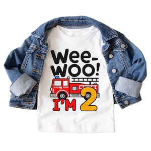 May include: White t-shirt with a red fire truck and the text "Wee-Woo! I'm 2" in black and yellow.