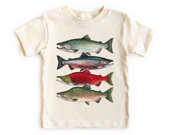 Könnte beinhalten: Cremefarbenes T-Shirt mit einer detaillierten Illustration von vier verschiedenen Fischarten. Die Fische sind in Grün-, Rot- und Silbertönen dargestellt, mit komplizierten Details. Das Shirt ist aus einem weichen, bequemen Material.