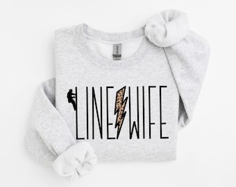 May include: A gray sweatshirt with the text "LINE WIFE" in black lettering. A leopard print lightning bolt graphic is centered between the words.