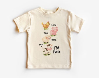 Puede incluir: Camiseta crema para niños pequeños con ilustraciones de acuarela de animales de granja: una gallina, un cerdo, una oveja y una vaca. Cada animal está etiquetado con su sonido, y el texto "I'M TWO" está impreso debajo.